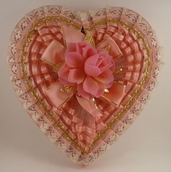 An antique Valentine's candy box, with pink and gold ribbons and a pink plastic rose.